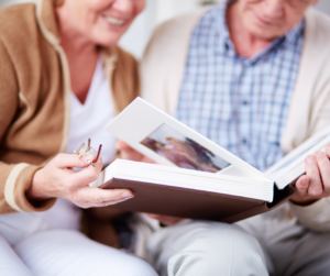 An elderly couple sat down looking through a photo album