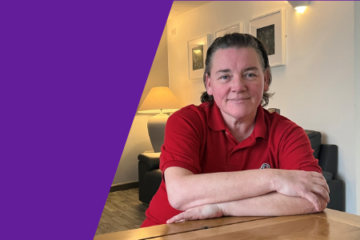 A purple graphic featuring an image of Sam Barlow, a team leader at Poppy Dementia Day Support. Sam, with short black hair, is sitting at a wooden table smiling.
